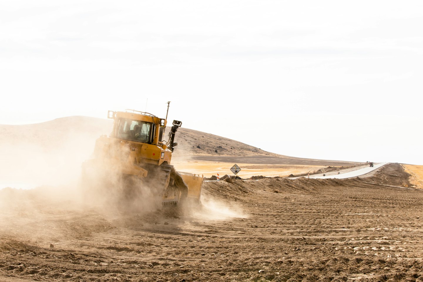 Yellow bulldozer pushes dirt on a construction site.