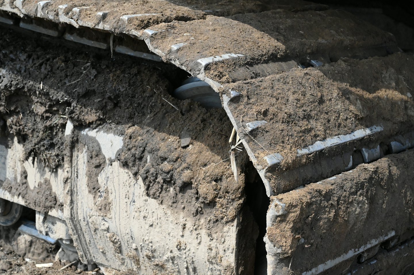 Muddy metal tracks on a heavy construction excavator.